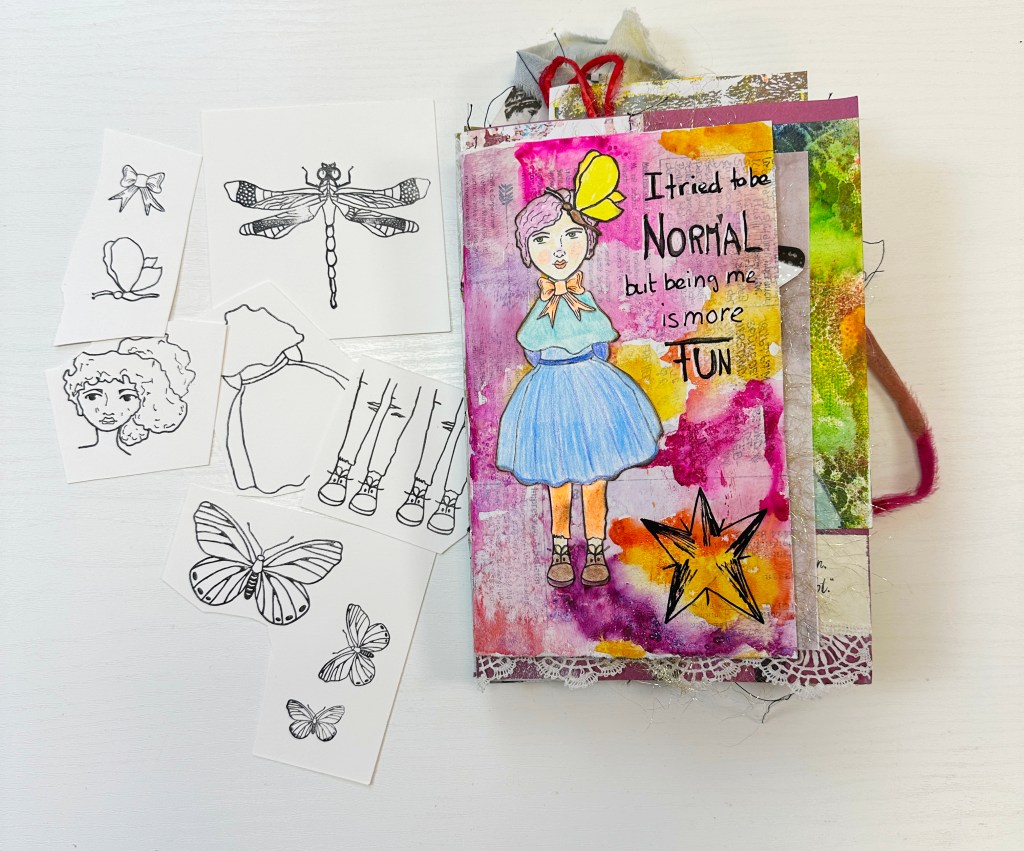 A colorful handmade journal featuring a whimsical drawing of a girl in a blue dress with a butterfly on her head, surrounded by various sketch designs of butterflies, flowers, and hair styles.