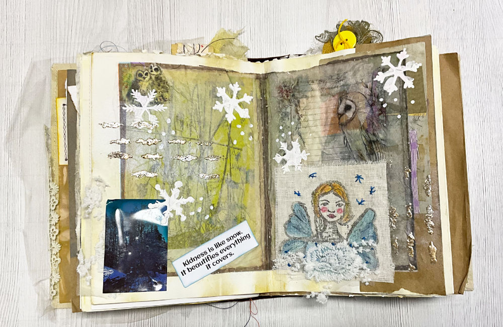 A creatively layered junk journal page featuring winter themes, including snowflakes, lace, a hand-drawn fabric winter fairy, and a photo of a snowy scene with an inspiring quote.