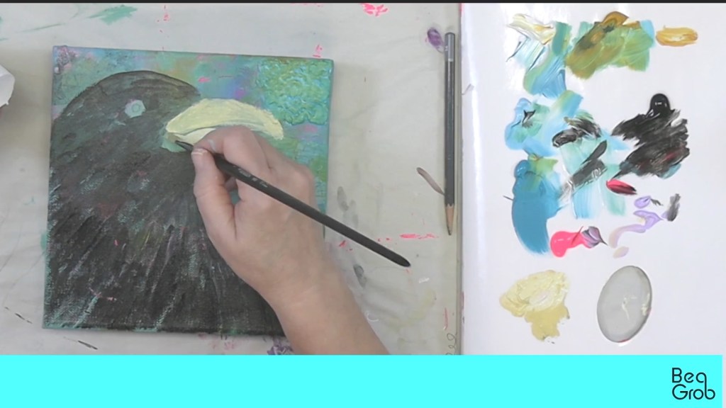 A person painting a close-up of a bird's head on a canvas, with a variety of colorful paint palettes visible beside them.