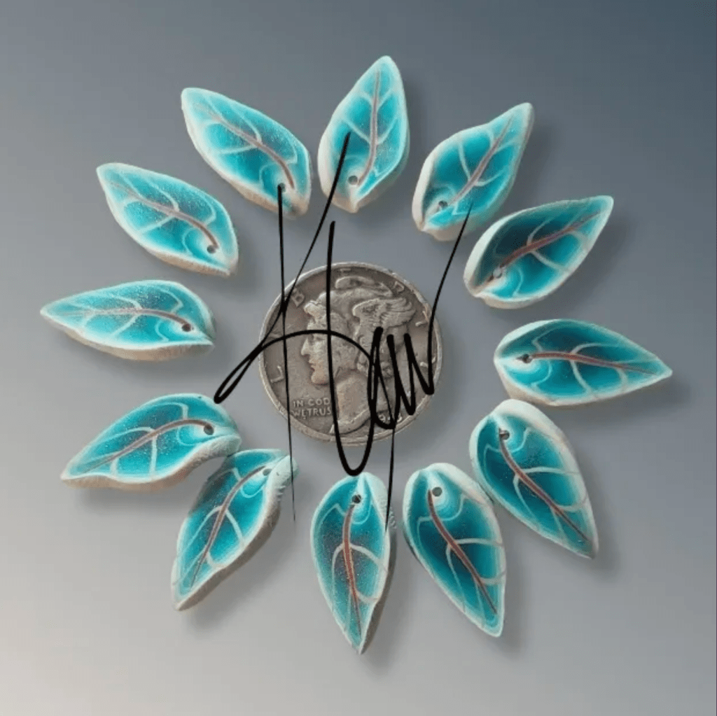 A circular arrangement of turquoise-colored leaf-shaped objects surrounding a coin on a light background.