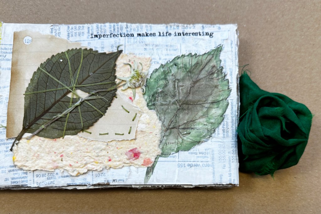 Mixed media journal page made from cardboard and old telephone book pages featuring a real dried leaf stitched with vintage thread, sketched and painted leaf, handmade paper, coffee-dyed paper, and tissue paper quote.