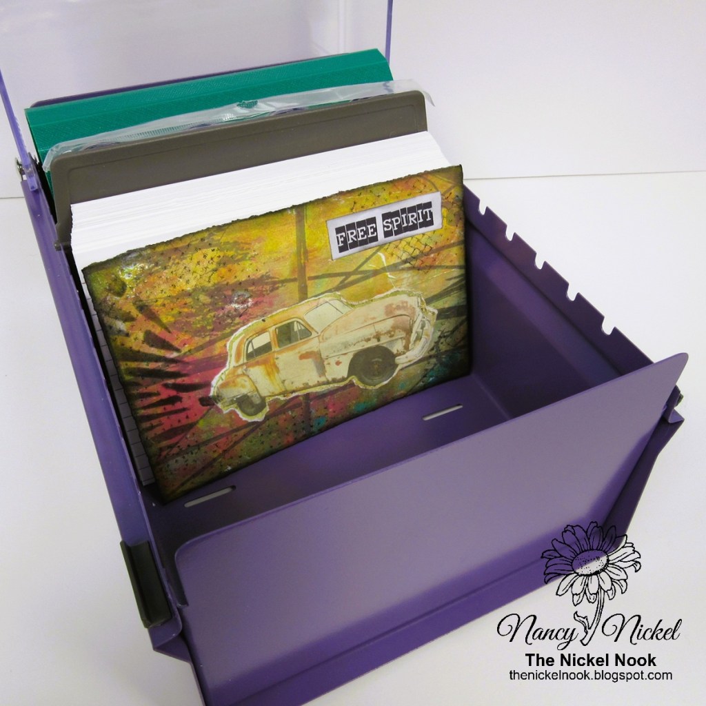 A purple storage box containing several colorful cardstocks and a prominently displayed artwork featuring a vintage car with the text 'FREE SPIRIT'.