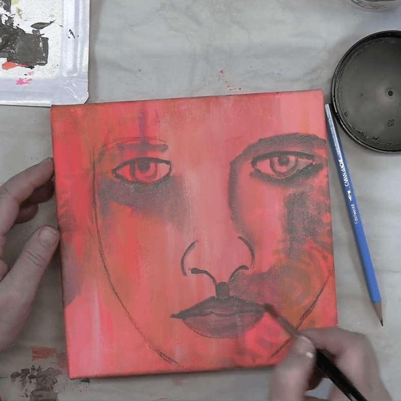 Close-up of a person's hand painting a face on a canvas with a pink background. The artwork features prominent eyes and lips, showcasing vibrant colors.